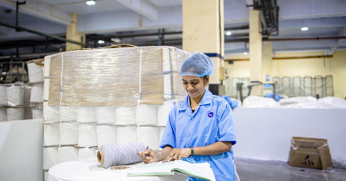 A factory worker records details in a textile manufacturing plant, showcasing industry and precision.